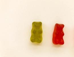 gummy bears of bright colors on a pink matte background. green and red transparent bear. delicious appetizing candies of an unusual shape, high-calorie dessert photo