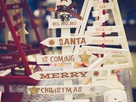 Wooden beautiful toy decorative Christmas cute festive Christmas trees with inscriptions of happy Christmas, Santa is coming. The background photo