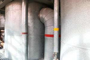 Large iron heat exchanger, tank, reactor, distillation column in thermal insulation of fiberglass and mineral wool of galvanized steel in the industrial refinery petrochemical plant shop photo