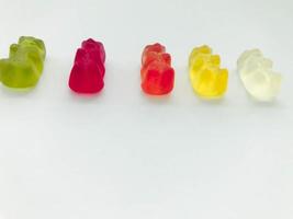 gummy bears of bright, different colors on a blue matte background. delicious mouth-watering candies of an unusual shape. high-calorie dessert. calories for weight gain, sugar sweetness photo