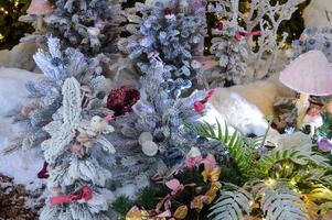 Close-up of a Christmas toy on a snow-covered lively tree in the winter forest on the background of lights photo