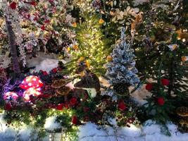 Christmas decorations on the tree. artificial spruce, beside it animals made of artificial materials. fox sits next to red mushrooms. showcase decoration for the new year photo