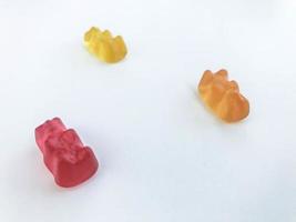 ositos de goma sobre un fondo blanco mate. el oso rojo, amarillo y naranja yacen sobre la mesa. deliciosos dulces, golosinas de personas. dulces de producción propia. dulces para decorar tartas y pasteles foto