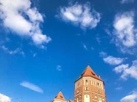 torres y agujas de un antiguo y hermoso castillo medieval de piedra alto contra un cielo azul foto