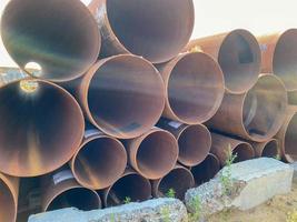 Lots of large diameter industrial iron rusty pipes with corrosion ready for installation plumbing for oil refinery petrochemical plant equipment at construction site photo