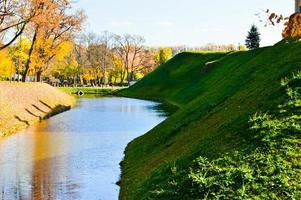 A large red brick earthen wall is strong protective and a moat with the war of an old, ancient medieval castle in the center of Europe against the blue sky photo