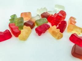 gummy candy on a white matte background. marmalade in the form of gelatinous bears lies on the table. mouth-watering sweet candies for kids and adults photo