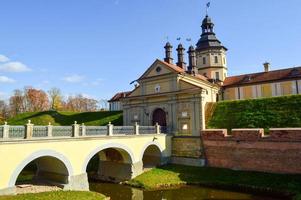 Old, ancient medieval castle with spiers and towers, walls of stone and brick surrounded by a protective moat with water in the center of Europe. Baroque style architecture photo