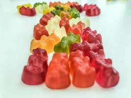 voluminous, bright gelatinous gummy bears. bears lie on a matte background. one row of bears. volumetric figure. sweet arrow from gummy bears. delicious bears on the table photo