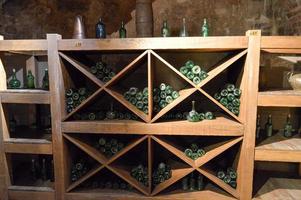botellas de vino y cerveza vacías de color verde vintage en un armario de vinos con estantes en una antigua bodega de piedra de ladrillo medieval