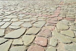 The texture of the stone road, pavement, walls of large gray old medieval round strong stones, cobblestones. The background photo