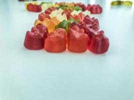 voluminous, bright gelatinous gummy bears. bears lie on a matte background. bears are stacked in one row in the shape of a figure. decorating cakes and desserts photo