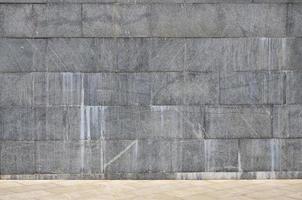 The texture of a wall of large granite tiles that are covered with white streaks when exposed to dampness
