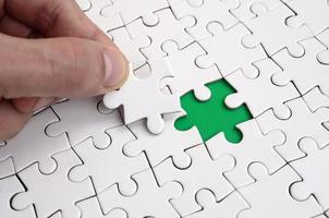 The human hand fills the last missing elements of the surface from the jigsaw puzzle. The concept of the completion of the initiated cases photo