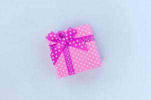 Small purple gift box with ribbon lies on a violet background photo