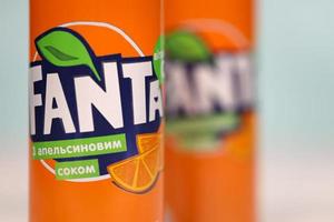 KHARKOV, UKRAINE - DECEMBER 8, 2020 Aluminium cans of Fanta soft drink on white wooden table. Fanta is brand of carbonated soft drinks created by The Coca-Cola Company in 1940 photo