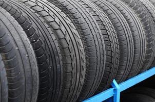 Rack with variety of car tires in automobile store. Many black tires. Tire stack background. Selective focus photo