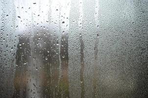 una foto de la superficie de vidrio de la ventana, cubierta con una multitud de gotas de varios tamaños. textura de fondo de una densa capa de condensado sobre vidrio