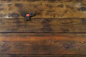 A rare handmade wooden fidget spinner lies on a brown wooden background surface. Trendy stress relieving toy photo