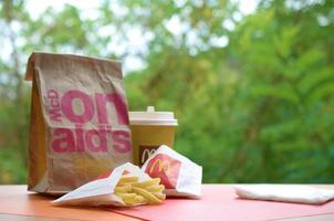 kharkov, ucrania - 9 de diciembre de 2020 bolsa de papel para llevar mcdonald's y comida chatarra en una mesa de madera al aire libre foto