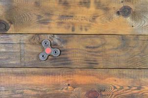 A rare handmade wooden fidget spinner lies on a brown wooden background surface. Trendy stress relieving toy photo