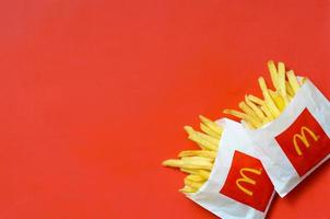 kharkov, ucrania - 9 de diciembre de 2020 papas fritas de mcdonald's en una pequeña bolsa de papel sobre fondo rojo brillante foto