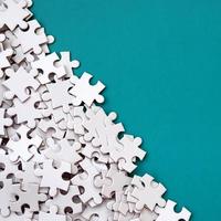 A pile of uncombed elements of a white jigsaw puzzle lies on the background of a blue surface. Texture photo with copy space for text
