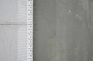 The texture of the wall, covered with gray polystyrene foam plates, which are coated with a reinforcing mixture with a plastic reinforcing profile corner. Stage of wall insulation photo