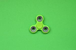 Green fidget spinner lies on texture background of fashion pastel green color paper in minimal concept photo