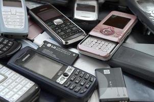 KHARKOV, UKRAINE - DECEMBER 9, 2020 Bunch of old used outdated mobile phones and batteries. Recycling electronics photo