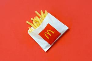 KHARKOV, UKRAINE - DECEMBER 9, 2020 McDonald's French fries in small paperbag on bright red background photo