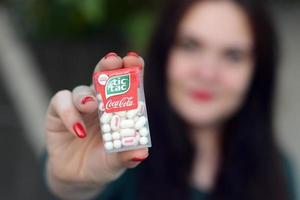 KHARKOV, UKRAINE - DECEMBER 9, 2020 Young girl holds Tic-tac hard mints pack with coca-cola taste. Tic Tac is a brand of small hard mints, produced by Ferrero photo