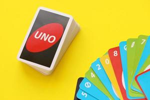 TERNOPIL, UKRAINE - MAY 15, 2022 Many colorful UNO game cards on yellow background. UNO is an American shedding-type card game that is played with a specially printed deck photo