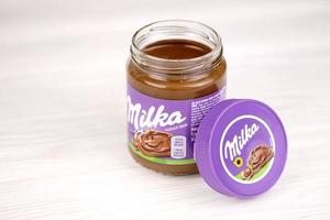 KHARKOV, UKRAINE - JULY 2, 2021 Can of Milka sweetened hazelnut cocoa spread with classical lilac color design on white table photo