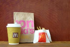 kharkov, ucrania - 9 de diciembre de 2020 bolsa de papel para llevar mcdonald's y comida chatarra en mesa de madera foto