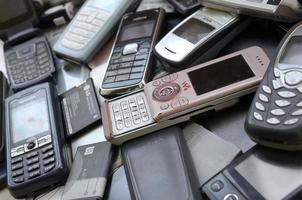 KHARKOV, UKRAINE - DECEMBER 9, 2020 Bunch of old used outdated mobile phones and batteries. Recycling electronics photo