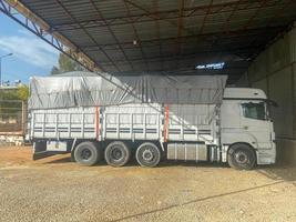 A large white powerful truck with an awning and a trailer is parked to unload cargo photo