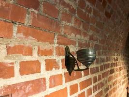 Old antique metal lamp holder on a red brick wall photo