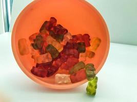 gummy bears of different colors lie in plastic and pink round shape. teddy bears are stacked in the kitchen in a kitchen sprinkler. delicious treat for children and adults photo