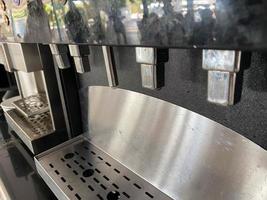 Shiny metal taps and tubes for pouring coffee from a coffee machine. Apparatus for hot drinks photo