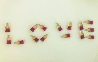 la palabra amor se presenta sobre un fondo de mermelada mate amarillo. caramelos de gelatina en forma de botellas con limonada. día de San Valentín. letras dulces y comestibles creativas foto