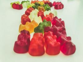 voluminous, bright gelatinous gummy bears. bears lie on a matte background. one row of bears. volumetric figure. bears are laid out in three rows. sweets for decorating cakes and pastries photo