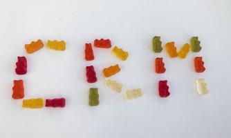 word from gummy gummy bears. edible letters C, R, M. vitamin and edible word. English alphabet. delicious appetizing dessert. bright bears on a white matte background photo