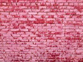 Texture of a beautiful unique unusual pink tender old cracked brick wall of rectangular bricks with seams painted with pink old shabby paint. The background photo