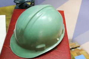 Green plastic safety helmet for the worker. Protective helmet to protect the head of people operating in hazardous conditions at the factory photo