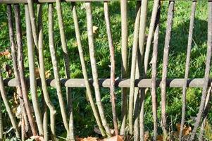 Wooden beautiful natural thin sticks, branches with bark intertwined in the fence against the background of green grass photo