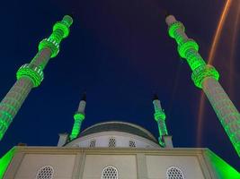 grande y hermosa mezquita musulmana alta templo islámico para rezar a dios allah con torres de alta religión en el cálido complejo tropical del este del país por la noche foto