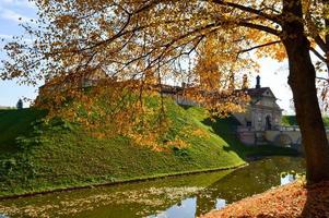 Old, ancient medieval castle with spiers and towers, walls of stone and brick surrounded by a protective moat with water in the center of Europe. Baroque style architecture photo