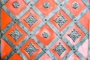 Texture of an old ancient medieval red antique sturdy iron metal door with rivets and nails patterns. The background photo