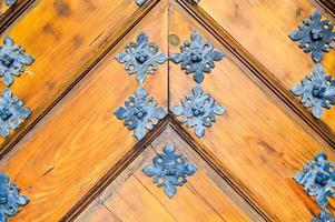 Texture of old ancient medieval antique sturdy wooden natural thick door with rivets and nails patterns and locks made of wooden planks. The background photo